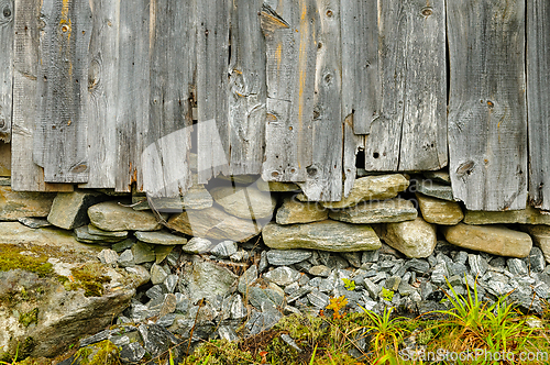 Image of Weathered wooden wall with rocky foundation and greenery in a qu