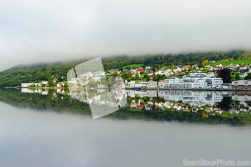 Image of Serene lakeside view of a quaint village reflecting in calm wate