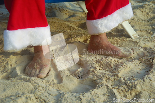 Image of Feet of Santa Claus on vacation on a tropical beach. 