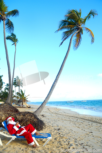 Image of Santa Claus is on vacation on a tropical beach. 