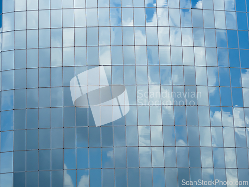 Image of Blue sky with clouds reflected in glass windows of skyscraper