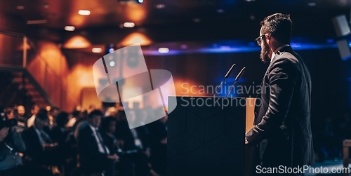 Image of Speaker giving a talk on corporate business conference. Unrecognizable people in audience at conference hall. Business and Entrepreneurship event