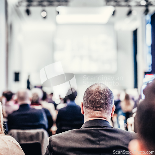 Image of Speaker giving a talk in conference hall at business event. Rear view of unrecognizable people in audience at the conference hall. Business and entrepreneurship concept.