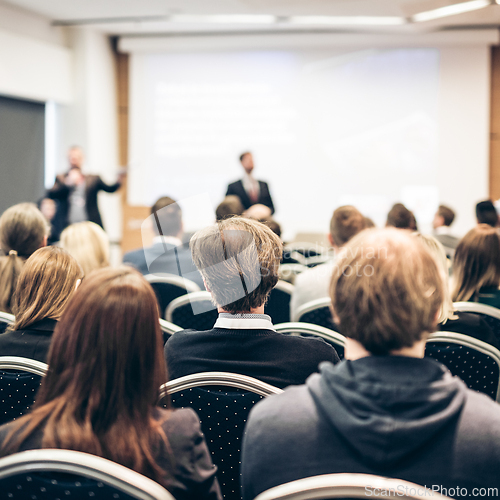 Image of Speaker giving a talk in conference hall at business event. Rear view of unrecognizable people in audience at the conference hall. Business and entrepreneurship concept.