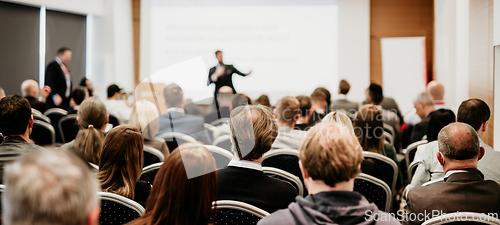 Image of Speaker giving a talk in conference hall at business event. Rear view of unrecognizable people in audience at the conference hall. Business and entrepreneurship concept.