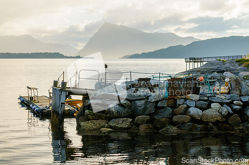 Image of Tranquil waterfront view with a rustic dock and mountains at sun