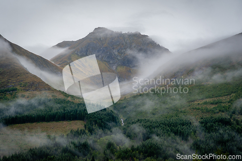 Image of Mountains shrouded in mist with lush green valleys and rugged pe