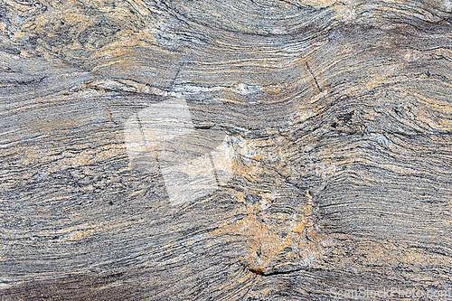 Image of Textured gray rock surface with wavy patterns and hints of orang