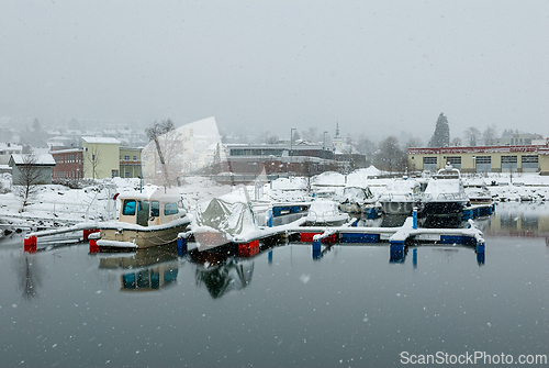 Image of Snow-covered boats docked in a tranquil harbor during winter's g