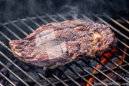 Image of steak grilling on charcoal grill