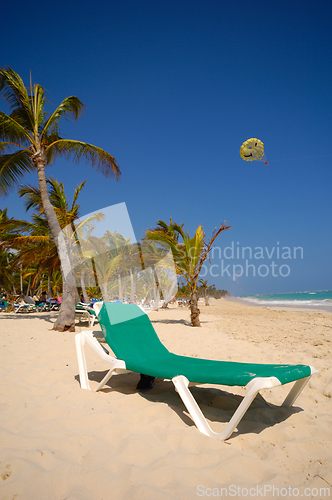 Image of A sun lounger and palm at exotic beach with white sand