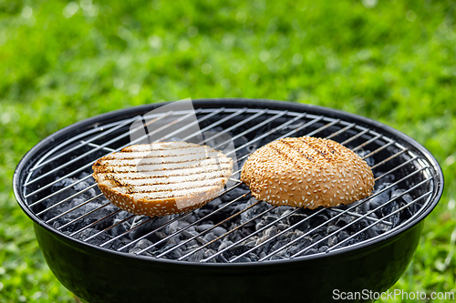 Image of burger bread bun grilling on charcoal grill