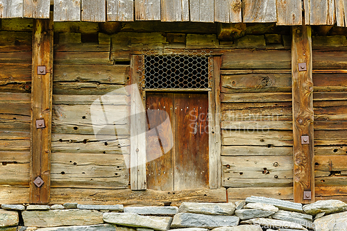 Image of Weathered wooden structure with a rustic door and stone foundati