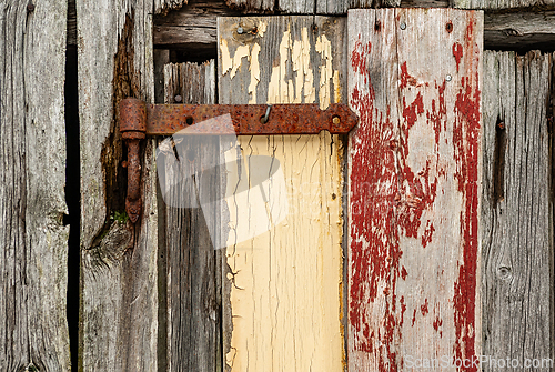 Image of A rustic door with peeling paint and a rusty hinge showcases the