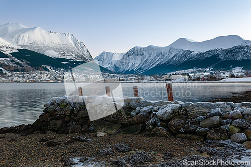 Image of Serene winter morning by the frozen shoreline, overlooking snow-