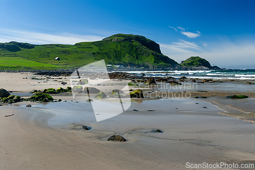Image of Serene coastal view at a remote beach with lush green hills and 