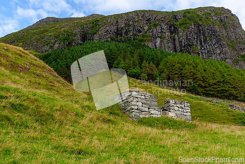 Image of Ruins nestled in a vibrant green valley under a dramatic mountai