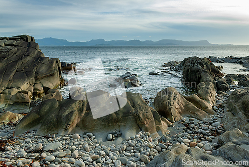 Image of Tranquil coastal landscape featuring rugged rocks and smooth peb