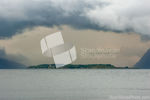 Image of A tranquil island emerges through shifting clouds over the seren