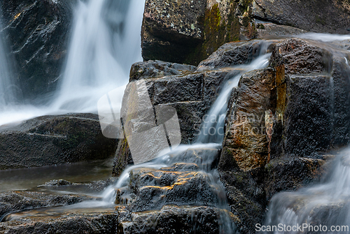 Image of Gentle water cascades over moss-covered stones in a tranquil for