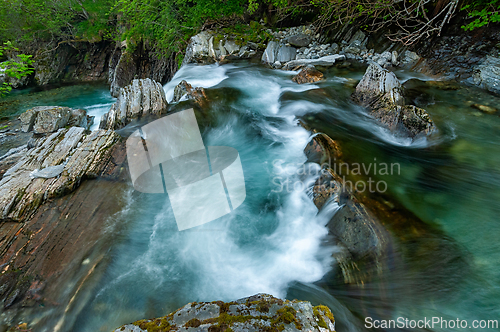 Image of A serene river flowing over smooth rocks, surrounded by lush gre
