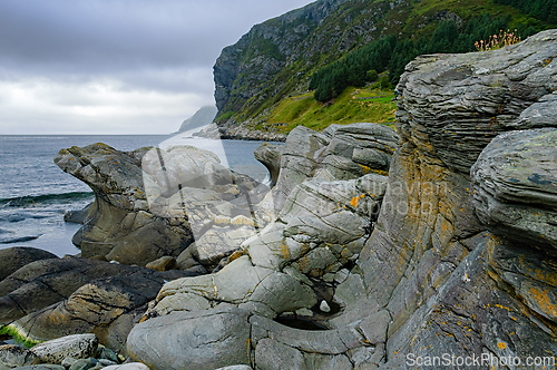Image of Waves gently lap against ancient rock formations along a rugged 