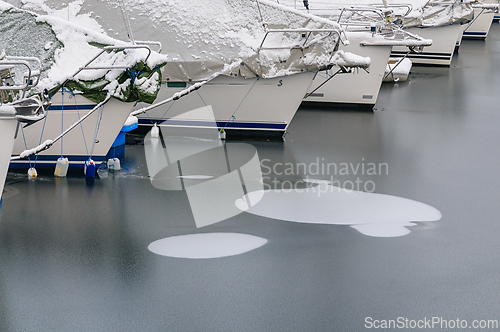 Image of Snow-covered boats moored peacefully in a serene harbor during a