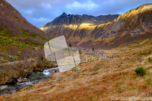 Image of Scenic valley beneath majestic mountains during golden hour refl