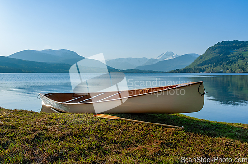 Image of A tranquil afternoon at the lake with a canoe on the shore, surr