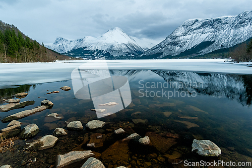 Image of Tranquil winter landscape reflecting snow-capped mountains over 