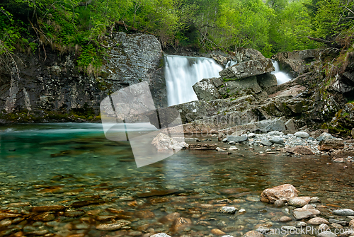 Image of Crystal-clear waters flow gently over rocks beneath a stunning w