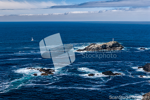 Image of A small island with a white lighthouse sits in the middle of the
