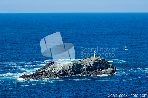 Image of A small, rocky island sits in the middle of a vast ocean, with a