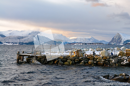 Image of A wooden dock extends out from a rocky shoreline, overlooking a 
