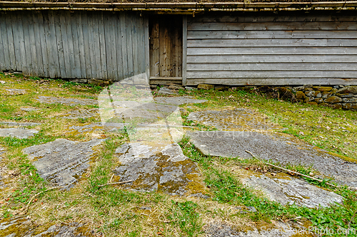 Image of A wooden building with a door stands on a hill covered in green 