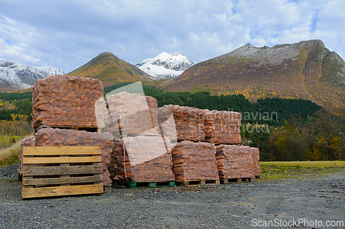 Image of Stacked firewood sits in front of a mountain range in Norway