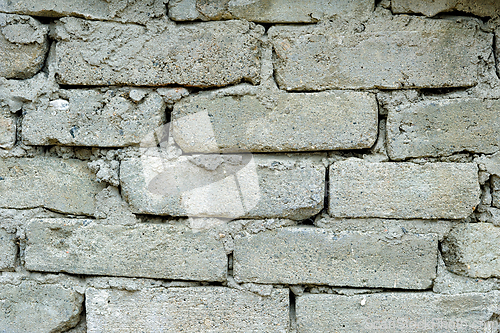Image of A close-up view of a gray brick wall with some missing mortar