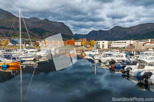 Image of A calm harbor in Norway with several boats docked along the shor