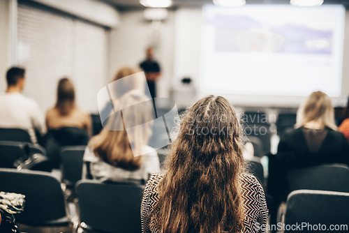 Image of Speaker giving a talk in conference hall at business event. Rear view of unrecognizable people in audience at the conference hall. Business and entrepreneurship concept.