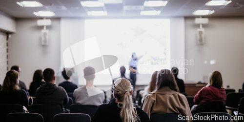 Image of Speaker giving a talk in conference hall at business event. Rear view of unrecognizable people in audience at the conference hall. Business and entrepreneurship concept.