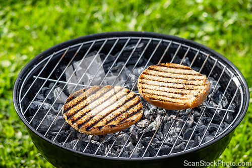 Image of burger bread bun grilling on charcoal grill