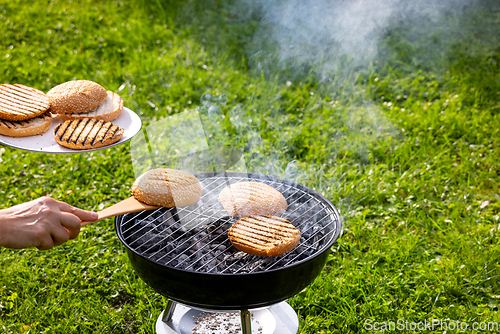 Image of burger bread bun grilling on charcoal grill