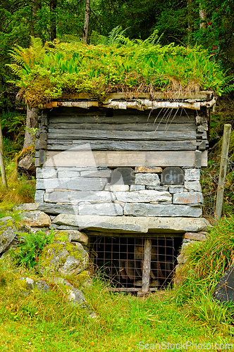Image of A small mill house with a green, mossy roof and a stone foundati