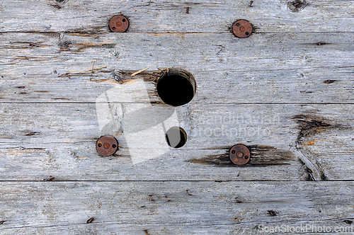 Image of A close-up of a weathered wooden surface with two holes and five