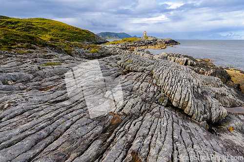 Image of A close-up view of the rocky shore of a small island, with a dis