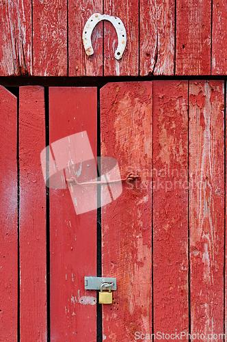 Image of Rustic red barn door adorned with a vintage horseshoe and a stur