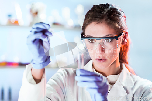 Image of Young scientist pipetting in life science laboratory.