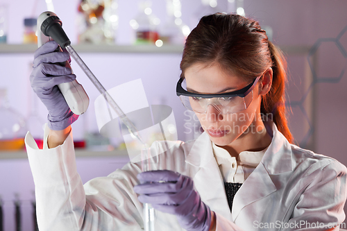 Image of Young scientist pipetting in life science laboratory.