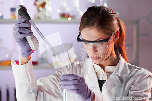 Image of Young scientist pipetting in life science laboratory.
