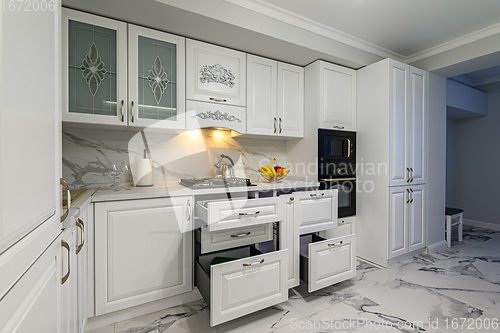 Image of Open drawers with kitchenware at modern white kitchen